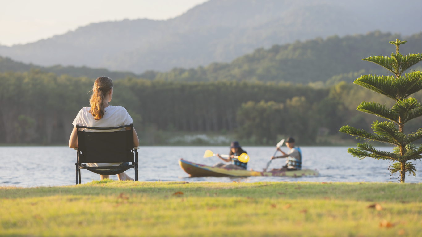 A woman relaxing by a scenic lake during as a full time RV vacation, enjoying peaceful natureal amenities.